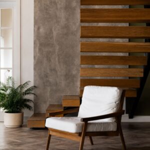 Modern wooden accent lounge chair with white cushions placed in a contemporary living room interior.